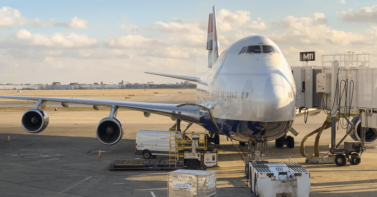 A plane docked at the airport loading merchandise.